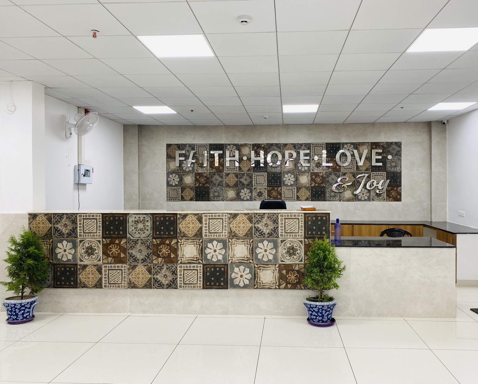 Trinity Hospitals reception desk with its decorative Faith, Hope, Love and Joy wall